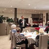 Zu sehen ist Christian Baron bei seiner Eröffnungsrede mit Mikrofon in der Hand im Restaurant Muckensee