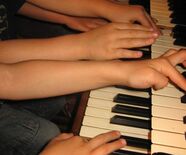 Bild von vielen Kindern an einem Klavier