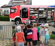 Eine Feuerwehrfrau der Feuerwehrabteilung Rehnenhof-Wetzgau erklärt Kindern der Kinderinsel Rehnenhof-Wetzgau ein Schild