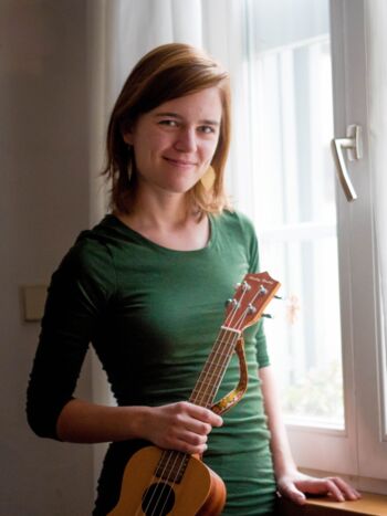 Portrait der Musikschul-Lehrerin Veronika Pasiziel in grünem Oberteil und Ukulele in der Hand. Sie lächelt freundlich in die Kamera.