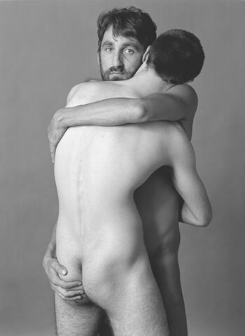 Ein schwarz-weiß Foto von zwei nackten Männer, die sich umarmen. Fotografiert 1980 von Helmut Röttgen.