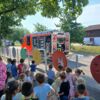 Zu sehen sind Kinder des Kinderhaus Emerlands und die Freiwillige Feuerwehr Straßdorf bei einer spannenden Brandschutzübung