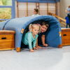 Zu sehen sind zwei Kinder in einer Turnhalle, versteckt unter einem Tunnel aus Sportmatten