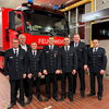 Zu sehen sind die beförderten Kameraden im Feuerwehrhaus vor einem Feuerwehrauto stehend