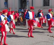 Zu sehen ist eine Parade in Faenza mit Personen auf dem Bild, die rot, weiß und blau gekleidet sind