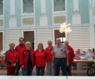 Zu sehen sind ein Teil der Ehrenamtlichen vor den Geschenketischen