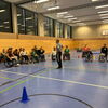 Zu sehen sind 10 Rollstuhlfahrer die sich in der Halle einem Parcours stellen.