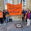 Zu sehen sind die Organisatorinnen des Aktionstages vor dem Rathaus stehend mit einem orangenen Spannbanner