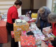Zu sehen sind drei Ehrenamtliche beim sortieren und platzieren der Geschenke im Prediger.