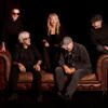 Die Musiker der Band sitzen auf einem braunen Ledersofa.