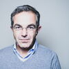 Navid Kermani im Porträt, randlose Brille, grau melierte Haare, grau-blauer Pullover