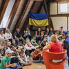 Zu sehen sind die Kinder in einem Halbkreis während sie der Vorleserin zuhören.