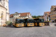 3 goldene Setra-Busse vor der Innenstadt-Kulisse