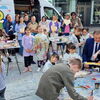 Zu sehen sind Kinder und Jugenliche bei der Bemalung der Holzherzen am Oberen Marktplatz